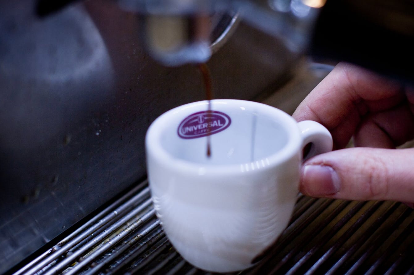 Máquina de espresso extraindo café em xícara no balcão da cafeteria